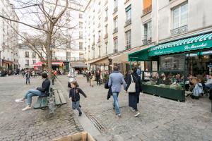 a group of people walking down a city street at Turenne Place Sainte Catherine in Paris
