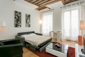 a bedroom with a bed and a couch and a table at Turenne Place Sainte Catherine in Paris