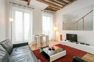 a living room with a couch and a tv at Le Marais Place Sainte Catherine With AC in Paris
