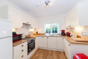 a white kitchen with white cabinets and a window at Prince Hill Cottages in Worton