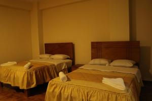 Dos camas en una habitación con toallas. en hotel el parral suite en Ica