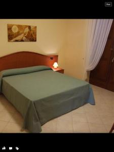 sypialnia z łóżkiem z zieloną narzutą w obiekcie Monte Degli Ulivi Country House w mieście Mercato San Severino