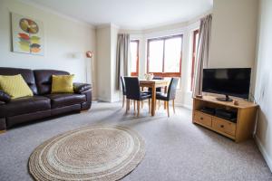 een woonkamer met een bank en een tafel met een televisie bij South Groathill - Lovely 2 bed with Castle View in Edinburgh