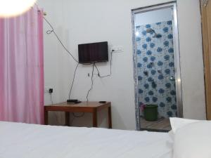 a bedroom with a bed and a television on the wall at Babusona Homestay in Jaldapara in Mādāri Hāt