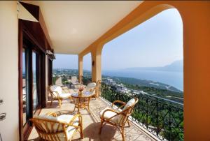 a balcony with chairs and tables and a view of the ocean at Villa Katerina-Despina in Argoulidhés