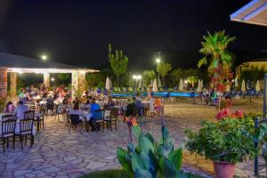 ペルディカにあるPerdika Resortの夜のレストランの椅子に座る人々