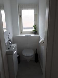 baño blanco con aseo y ventana en Ferienwohnung Frühlingsau en Freudenstadt