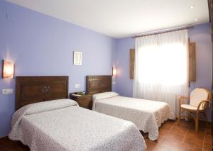 two beds in a room with blue walls and a window at Hotel Rural Suquin in Navia