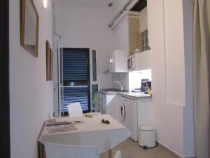 a small white kitchen with a white table and chairs at Villa Amalia Suites Malaga in Málaga