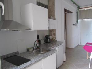 a kitchen with white cabinets and a sink at Villa Amalia Suites Malaga in Málaga