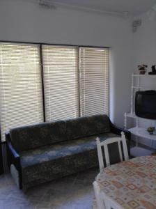 a living room with a couch in front of windows at Rozs Ház in Zalakaros