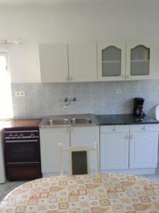 a kitchen with white cabinets and a sink and a stove at Rozs Ház in Zalakaros