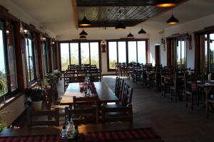 a restaurant with wooden tables and chairs and windows at Leshtenski Perli in Leshten