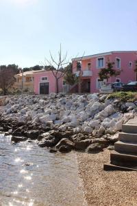 a rocky shore with some pink buildings in the background at Apartments Zvone1 - at water front in Veli Rat