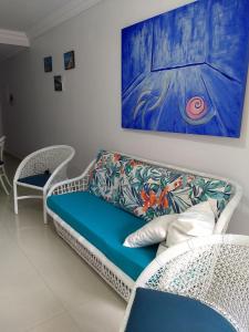 a couch in a room with a painting on the wall at Apto Novo a uma Quadra da Praia in Guarujá