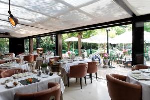a restaurant with white tables and chairs and windows at CAZAUDEHORE Hôtel Restaurant Gastronomique Terrasse et Jardins in Saint-Germain-en-Laye