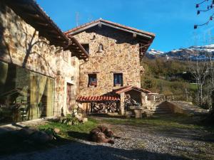 una casa de piedra con un perro tirado frente a ella en Caseria la Infiesta, en Caleao