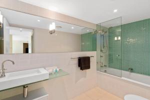 a bathroom with a shower, sink, and mirror at Solnamara Beachfront Apartments in Gold Coast