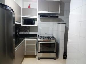a kitchen with white cabinets and a stove top oven at NOVO EDIFICIO VIENA - ATRAS do PRAIA CENTER in Guarapari
