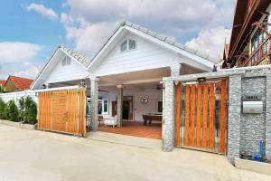 a house with a wooden gate in a driveway at Gala Villa Pattaya in Pattaya South
