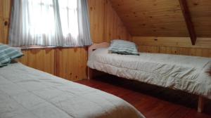 a bedroom with two beds in a log cabin at Cabañas la soñada in Chascomús