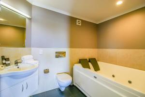 a bathroom with a sink and a tub and a toilet at Aotea Motor Lodge in Whanganui