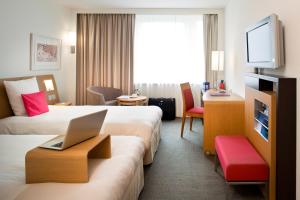 a hotel room with two beds and a laptop on a table at Novotel Zürich Airport Messe in Glattbrugg