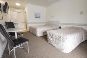 a hotel room with two beds and a table and a desk at Centretown Motel in Nagambie