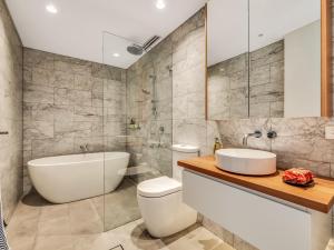 a bathroom with a tub and a toilet and a sink at Tamarama Apartments in Sydney