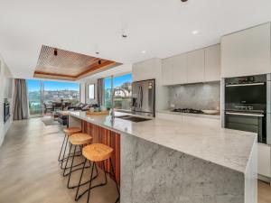 a kitchen with white cabinets and a counter with stools at Tamarama Apartments in Sydney