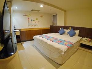 een slaapkamer met een groot wit bed met blauwe kussens bij Galaxy Hotel in Zhongli