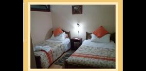 a bedroom with two beds and a night stand with a lamp at Hospedaje klickmann in Temuco
