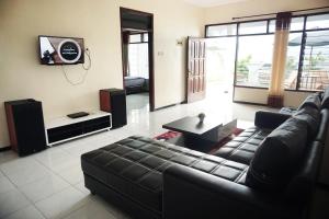 a living room with a leather couch and a tv at Villa Cemara in Batu