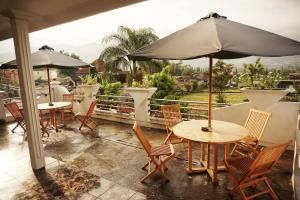 um pátio com mesas e cadeiras e um guarda-sol em Villa Cemara em Batu