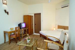 a hotel room with a bed and a table and a television at Deshadan Cliff & Beach Resort,Varkala in Varkala