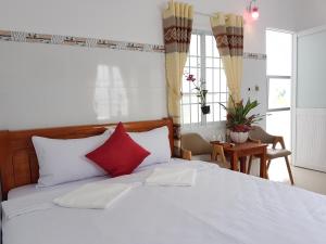 una camera da letto con un grande letto bianco con cuscini rossi di Song Ngoc Guesthouse a Phu Quoc