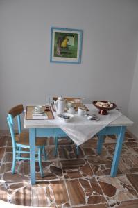 une table et des chaises bleues avec une table et une photo dans l'établissement Pà Blanc B&B, à Alghero