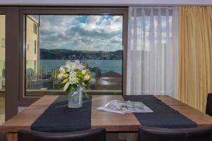 einen Esstisch mit einer Vase aus Blumen und einem großen Fenster in der Unterkunft Feri Suites in Istanbul