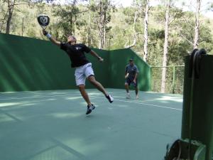 Un uomo che dondola una racchetta da tennis su un campo da tennis di Pousada Paraiso a Itaipava