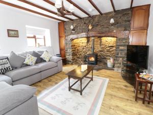 a living room with a couch and a stone fireplace at Garth Cottage in Denbigh