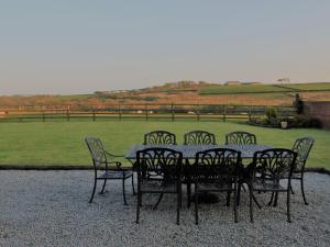 a dining table and chairs with a view of a field at Higher Forda in Bradworthy