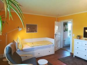 WalkendorfにあるParkland-Haus Dalwitzのオレンジ色の壁のベッドルーム1室、ベッド1台、椅子1脚が備わります。