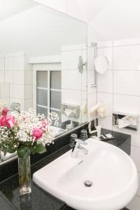 a bathroom with a sink and a vase of flowers at Apart Hotel Haveltreff in Caputh