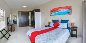 1 dormitorio con 1 cama grande con almohadas azules y rojas en JoJo's BnB, en Mossel Bay