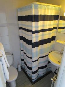 e bagno con tenda per la doccia, servizi igienici e lavandino. di Hotel Cafe Woud a Den Helder