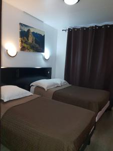 a hotel room with two beds and a painting on the wall at Hotel Victory in Marseille