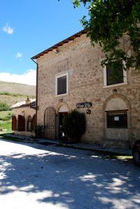 - un grand bâtiment en briques avec une porte devant dans l'établissement La Locanda sul Lago, à Santo Stefano di Sessanio