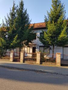 a building with a fence and trees in front of it at Pokoje pod Świerkiem in Swarzędz