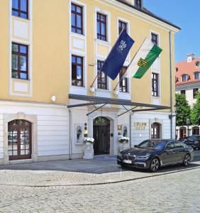 a car parked in front of a building with flags at Relais & Châteaux Bülow Palais in Dresden