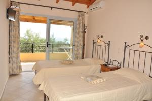 two beds in a room with a balcony at Lidovois House in Pelekas